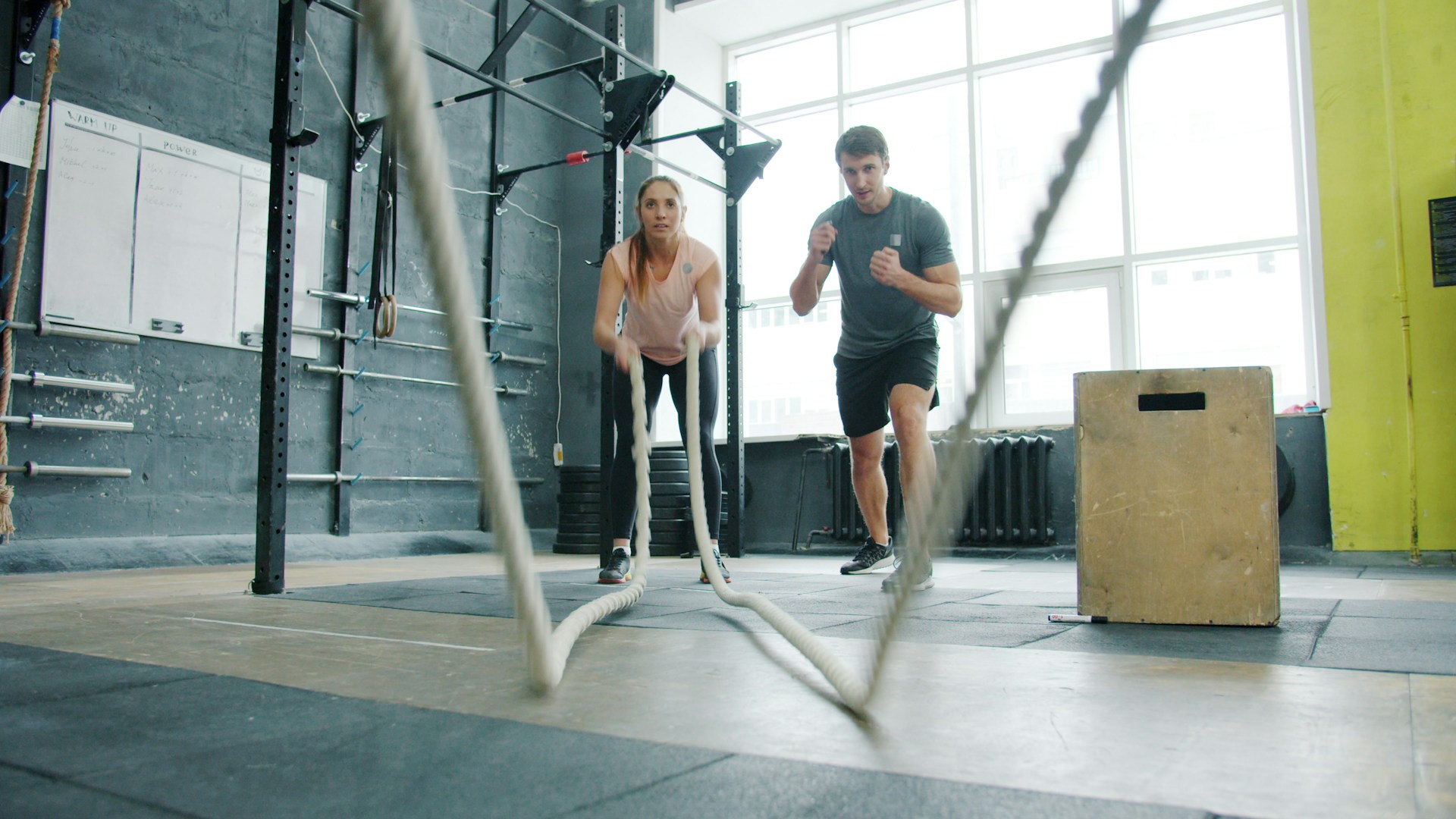 Two athletes exercising with battle ropes during a high-intensity gym workout