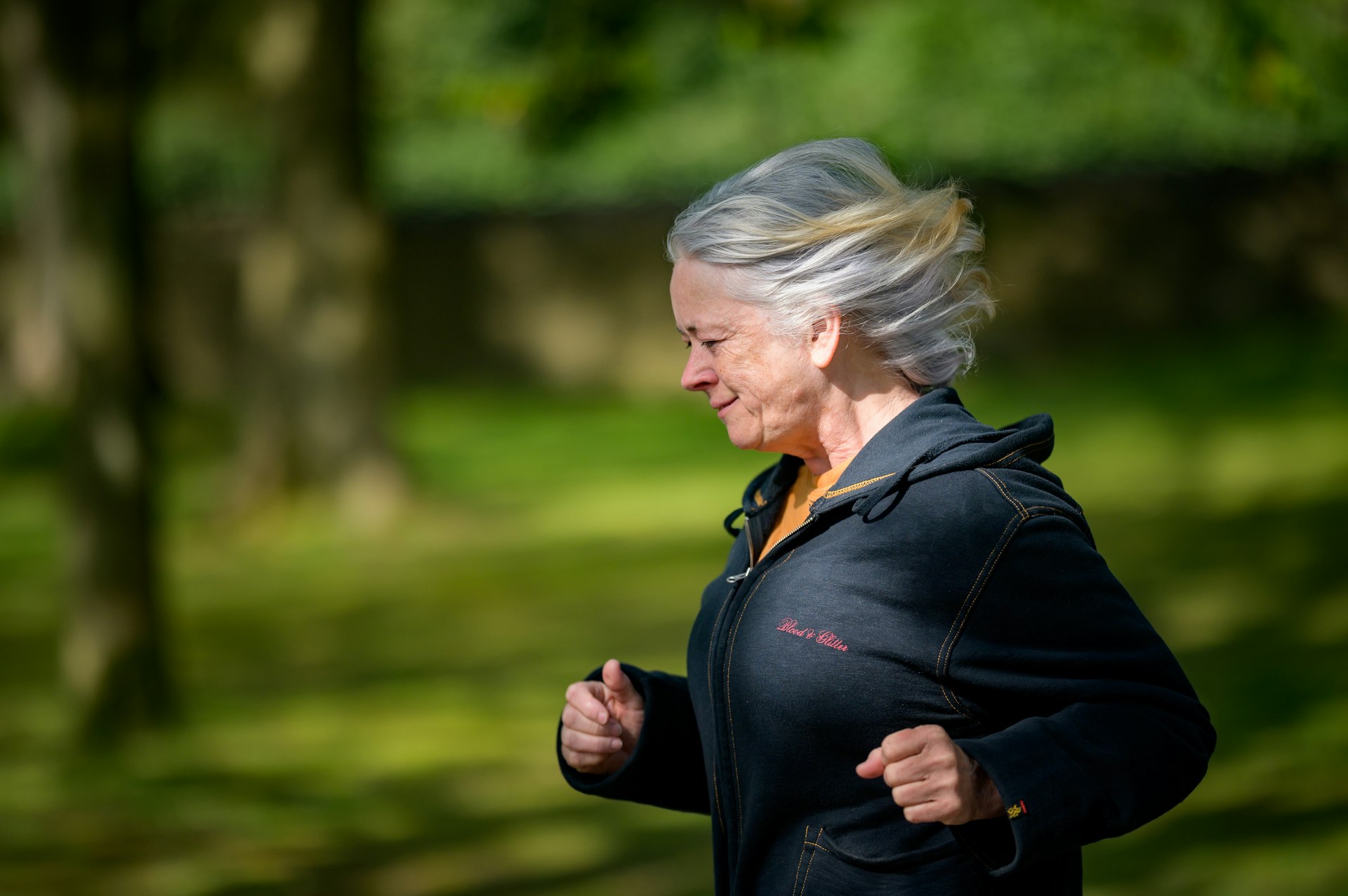 Silver-haired masters athlete running in a park, illustrating hydration strategies for athletes over 50