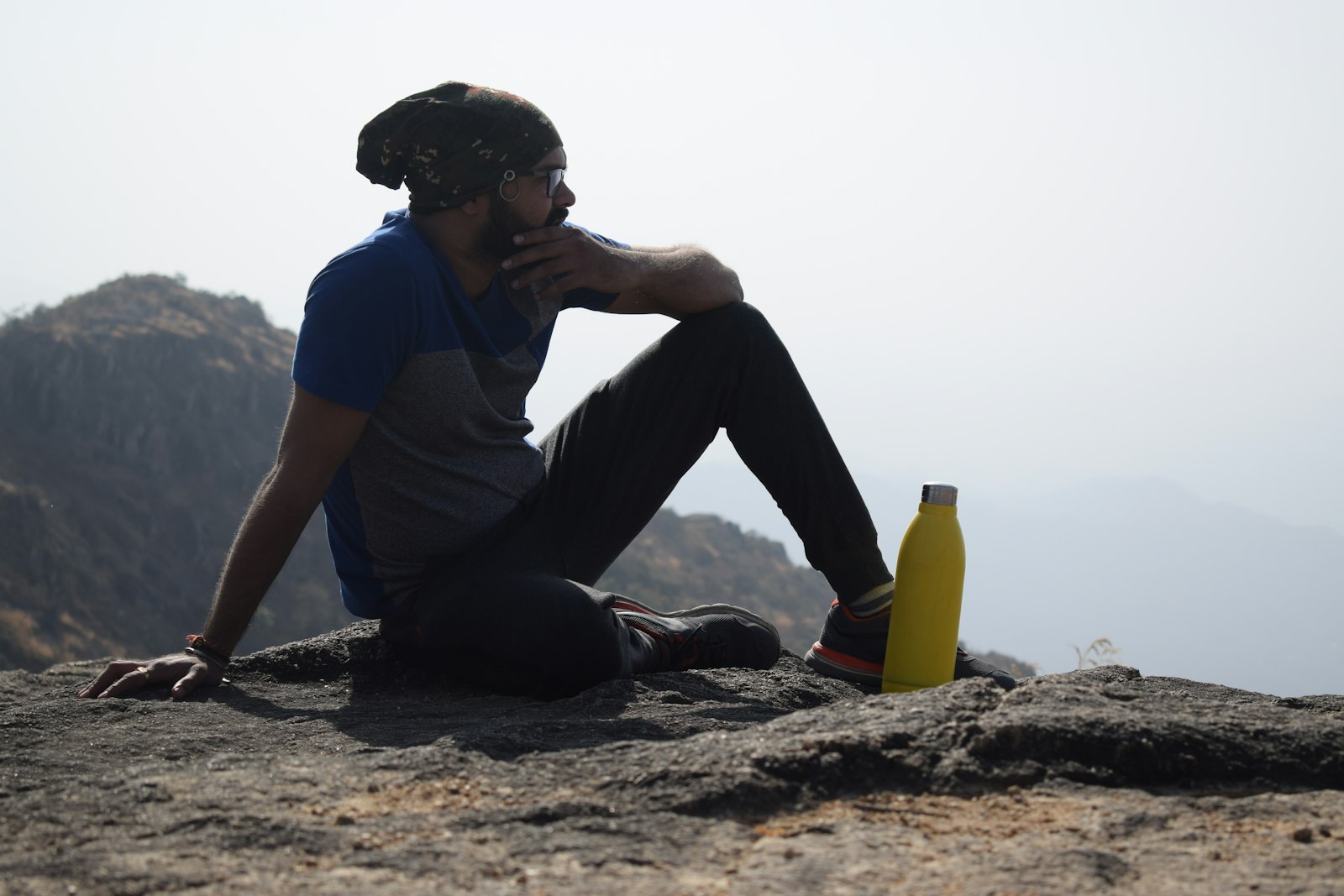 Endurance athlete resting on a mountain ridge with a yellow water bottle - sodium pre-loading