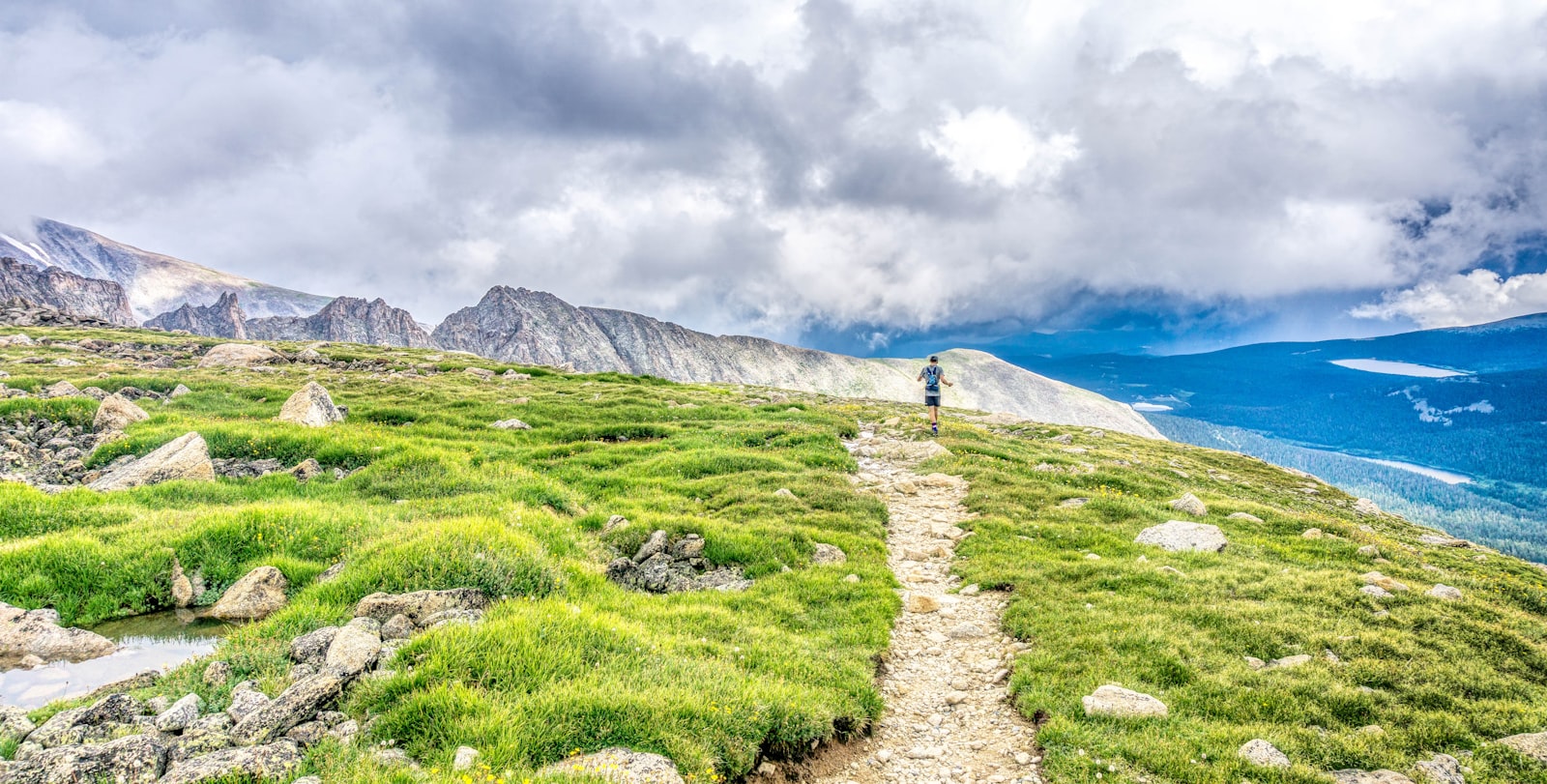 Trail runner on a mountain path carrying hydration gear