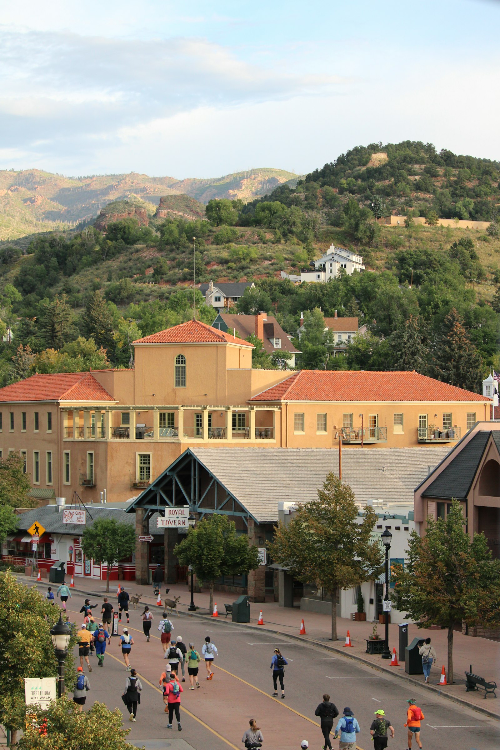 Runners racing down a road with hills and buildings — illustrating altitude hydration demands for high-elevation road races like the Bolder Boulder 10K.