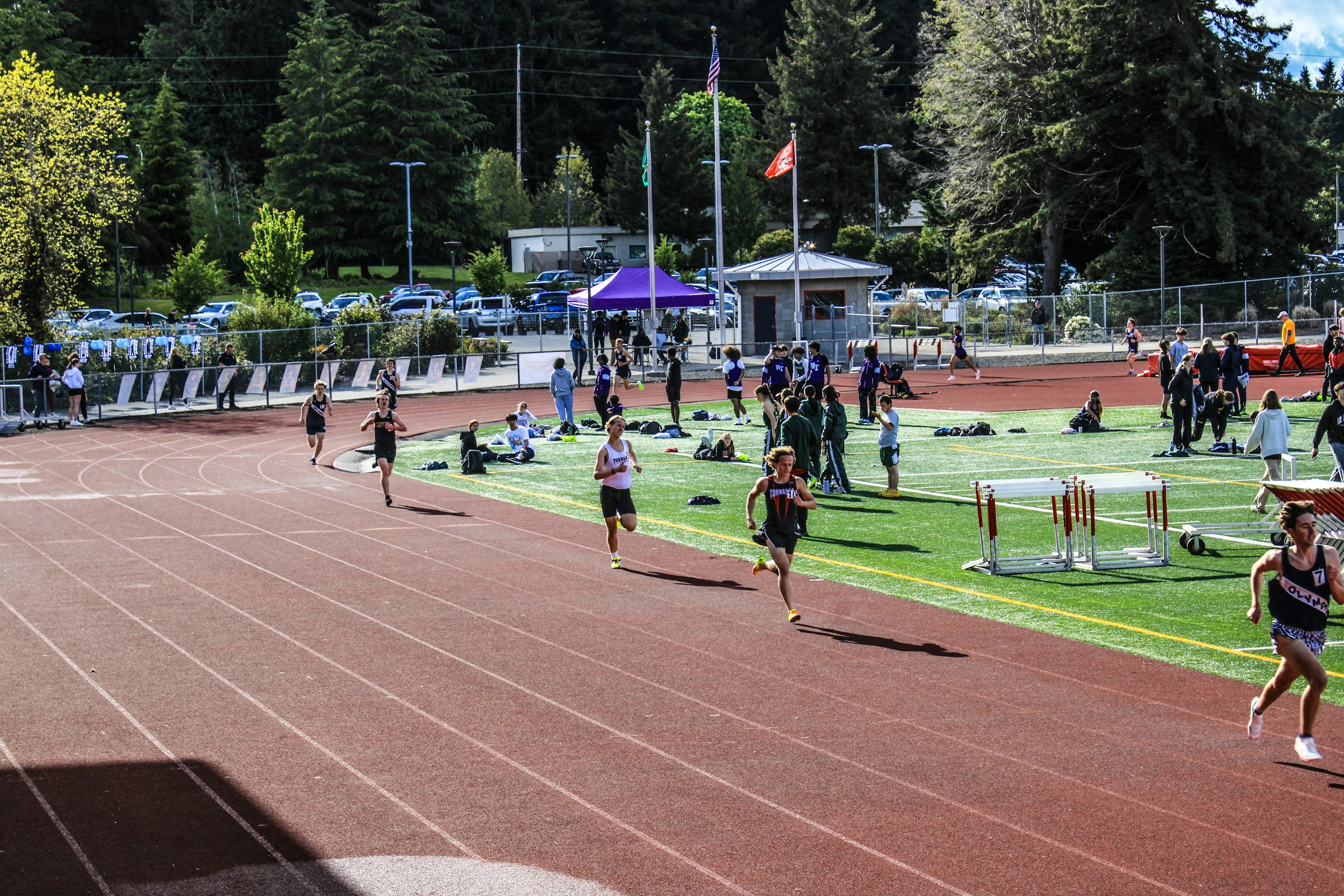 Group of runners training on an outdoor track during a sunny afternoon meet — heat acclimation block illustration