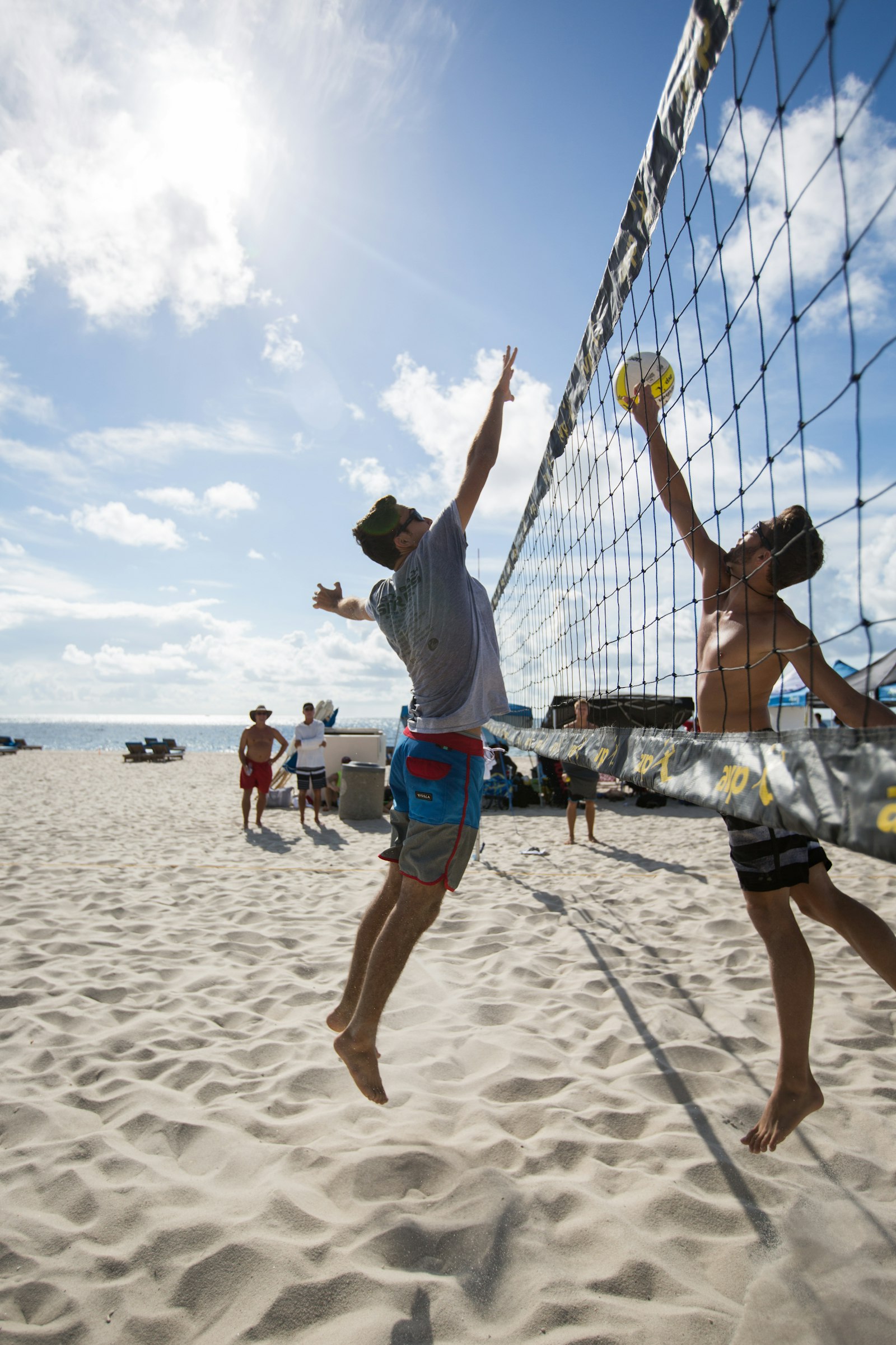 Male beach volleyball player on a sandy court mid-play — illustrating the heat and hydration demands of beach volleyball.