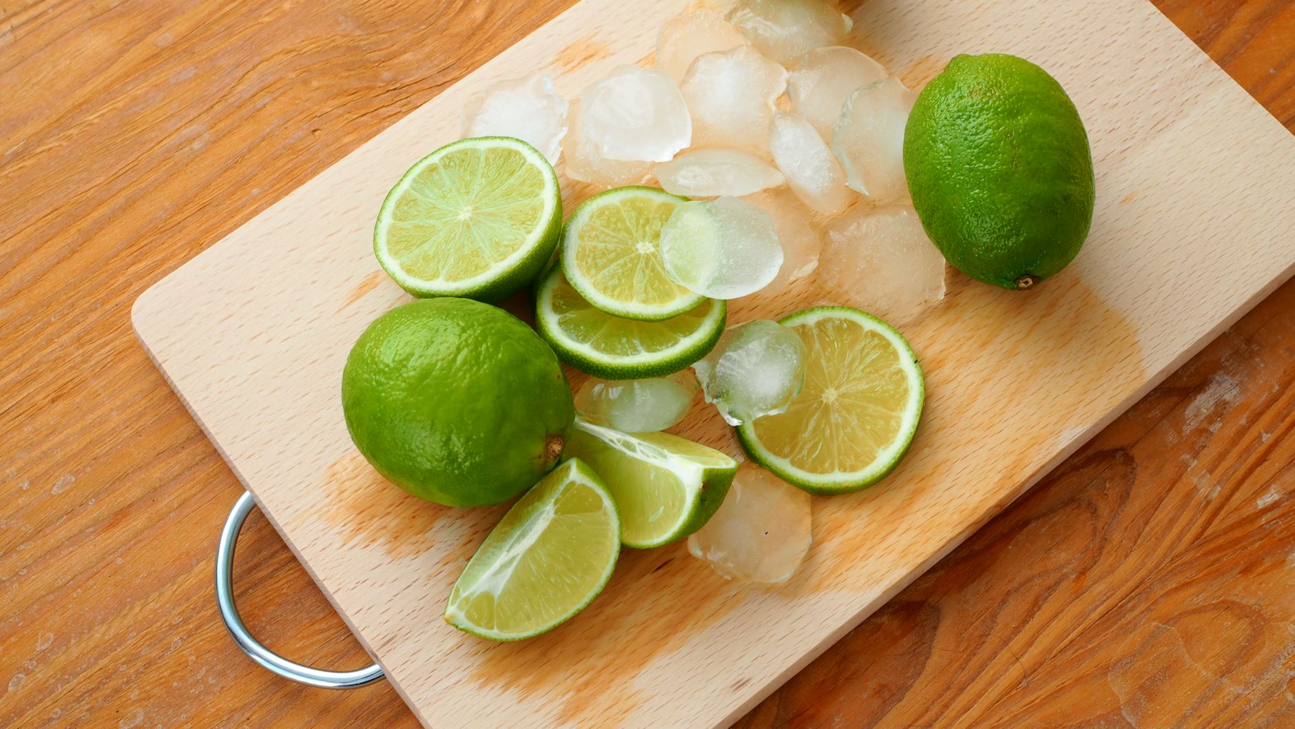 Sliced limes and ice cubes on a wooden chopping board for a fresh, summery feel.