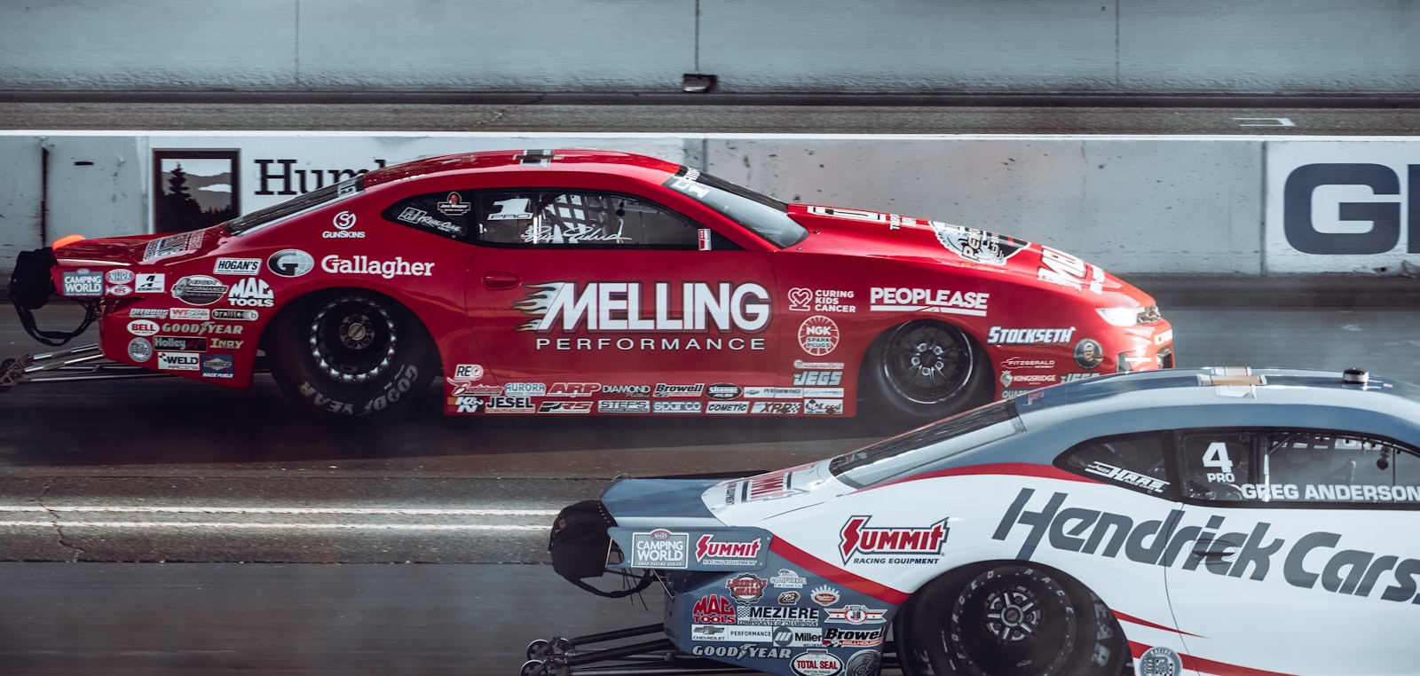 Two endurance sports cars racing wheel-to-wheel on track — illustrating the 24-hour heat and hydration demands of Le Mans-style endurance racing.