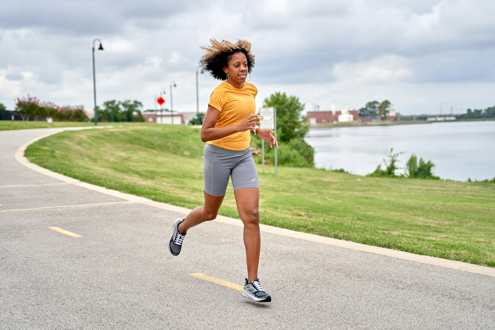 A runner on a road beside a lake, illustrating endurance exercise where muscle cramps commonly occur