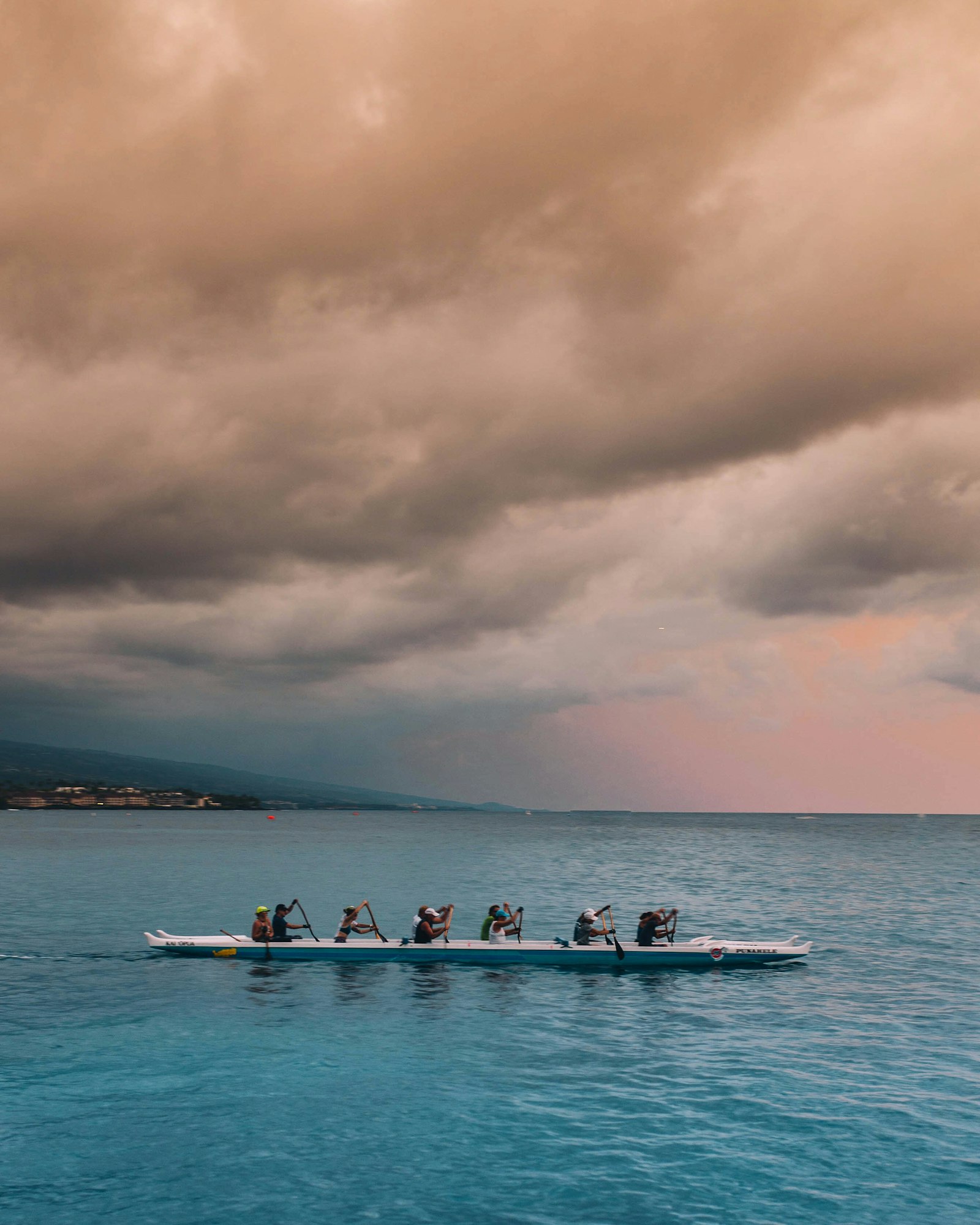 Rowing crew pulling through choppy open water under gray skies — illustrating the sweat, heat, and hydration demands of multi-race regatta days.