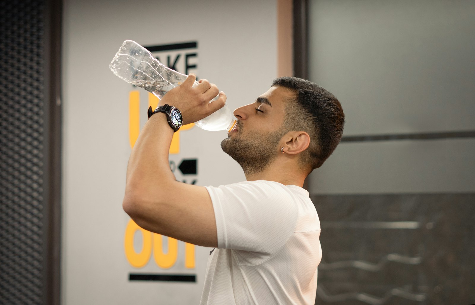 Athlete drinking water from a bottle in the gym during a workout