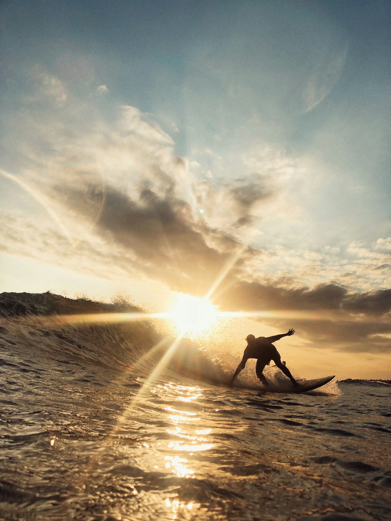 Surfer riding a wave at sunset — illustrating the hydration and sodium demands of ocean surf sessions.