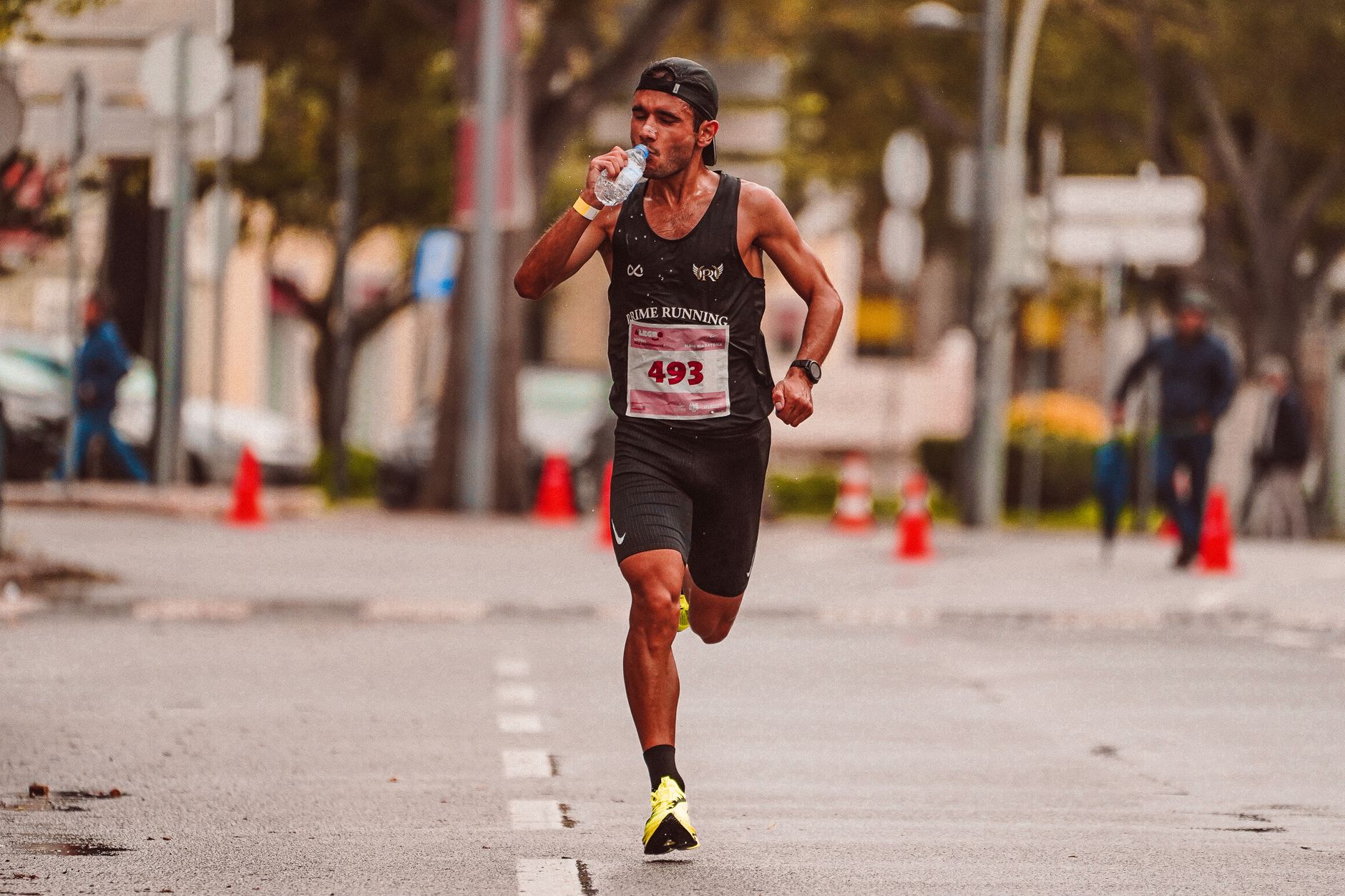 Athlete running in a marathon, staying hydrated. Outdoor city street scene.