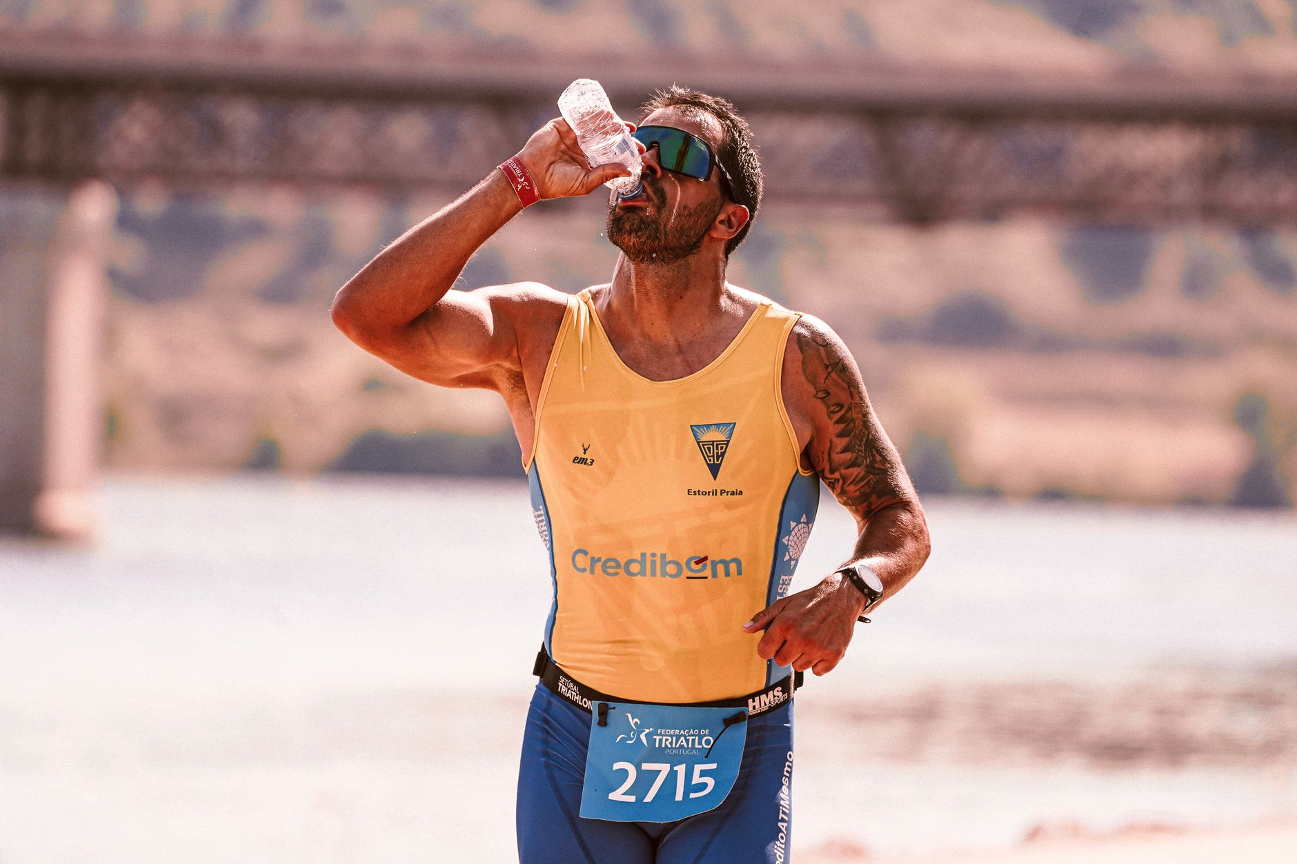 A focused male athlete drinks water while running in a marathon, showcasing endurance.