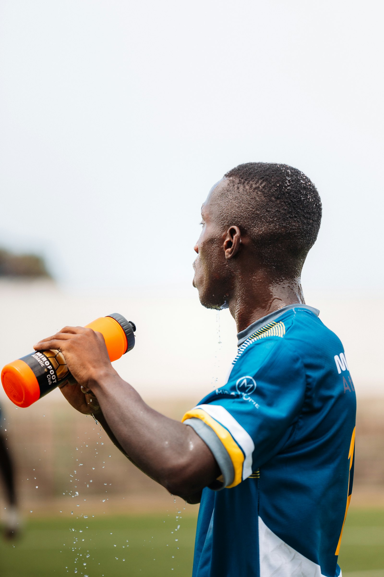 Athlete drinking water from a bottle on the field during practice