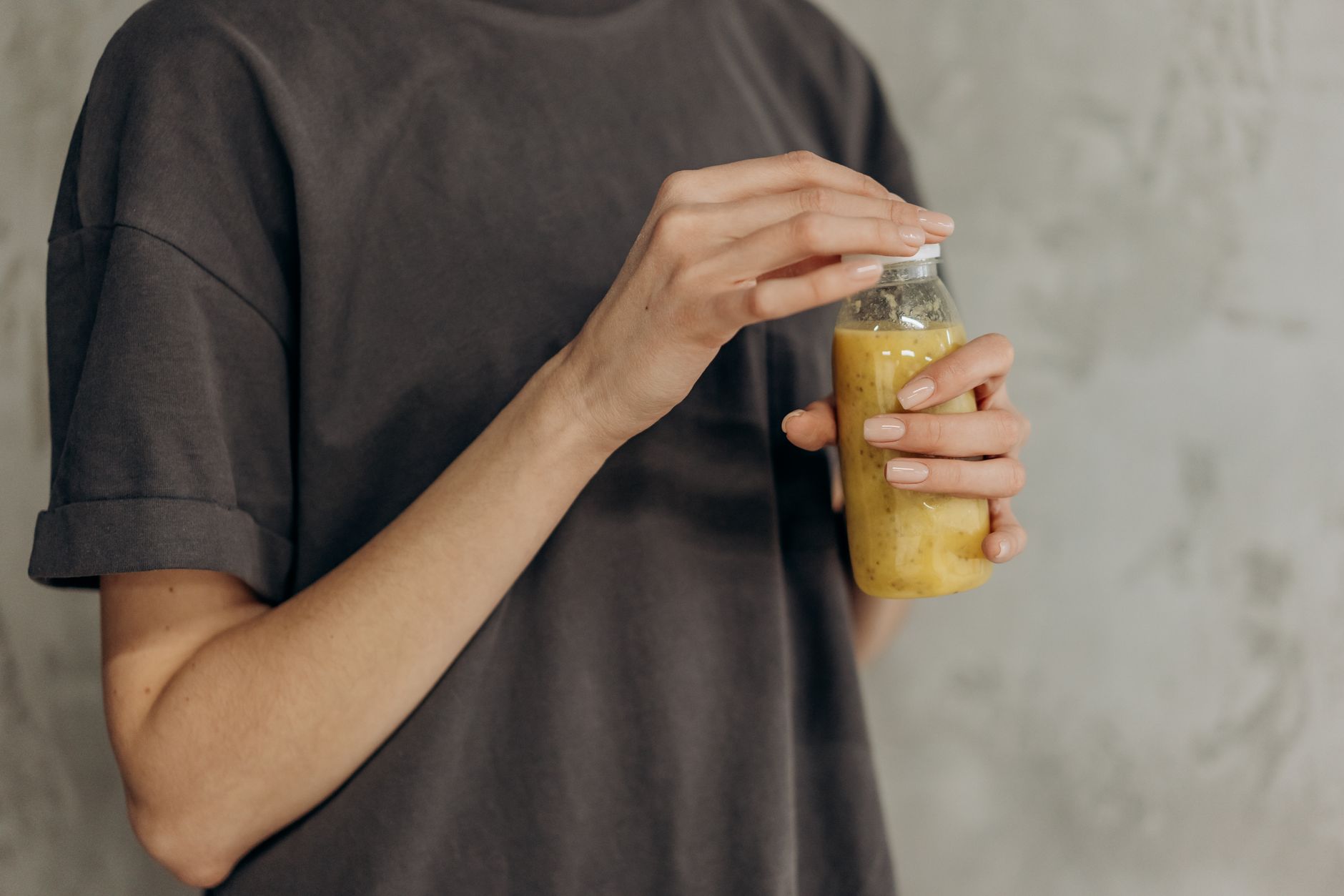 Close-up of a person holding a fresh smoothie bottle, symbolizing a healthy lifestyle.