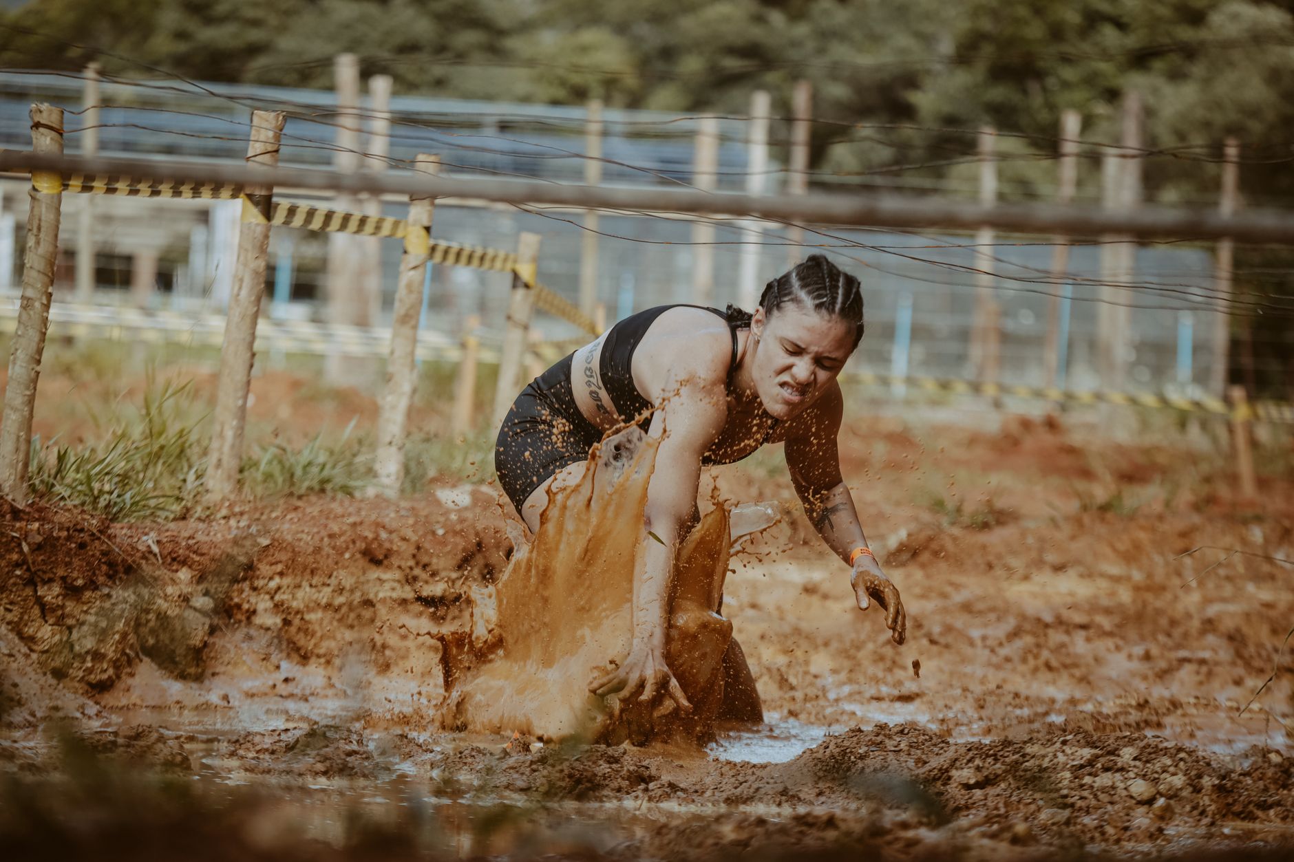 Female athlete tackling a muddy obstacle race, showcasing strength and determination outdoors.